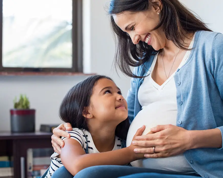 Photo of a pregnant woman embracing a child