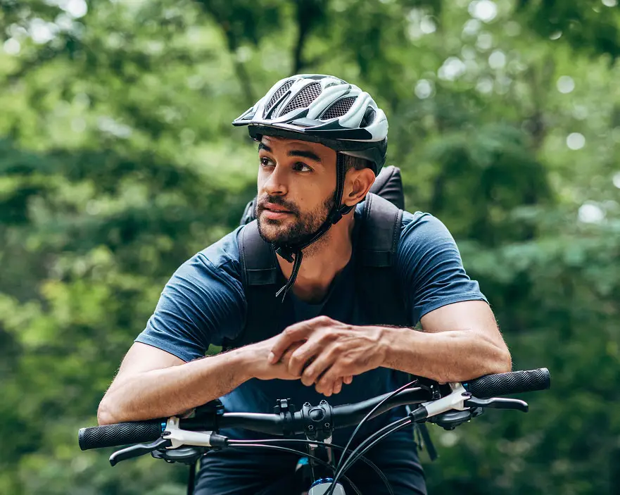 Photo of a man wearing a bike helmet and leaning on the handlebars of a bike