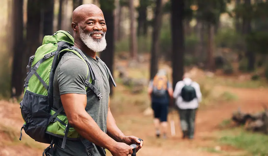 Photo of a smiling man hiking with other hikers in the background